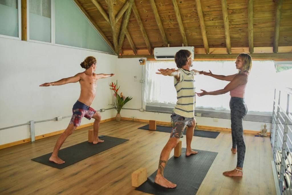 A yoga studio with wooden beams, black mats, and a view of the outdoors.
