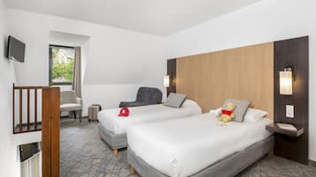 A hotel room with two beds, a TV, a wooden headboard, and a window with a view of greenery.