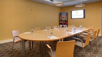 A conference room with a large table, chairs, and a projector screen displaying the Eliseo logo.