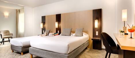 A hotel room with two beds, a desk, and a chair.