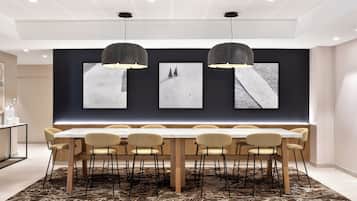 A modern dining area with a long table, multiple chairs, and pendant lighting.