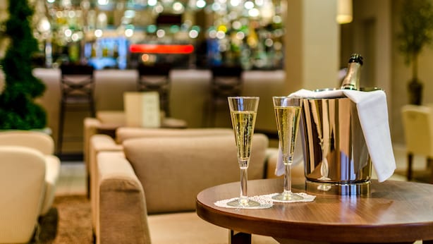 Un coin bar avec deux coupes à champagne posées sur une table, une bouteille de champagne et un comptoir de bar en arrière-plan.