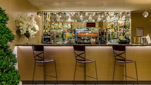 Un espace bar avec un comptoir, trois tabourets, une variété de bouteilles et une enseigne sur laquelle on peut lire « KIMBO ».
