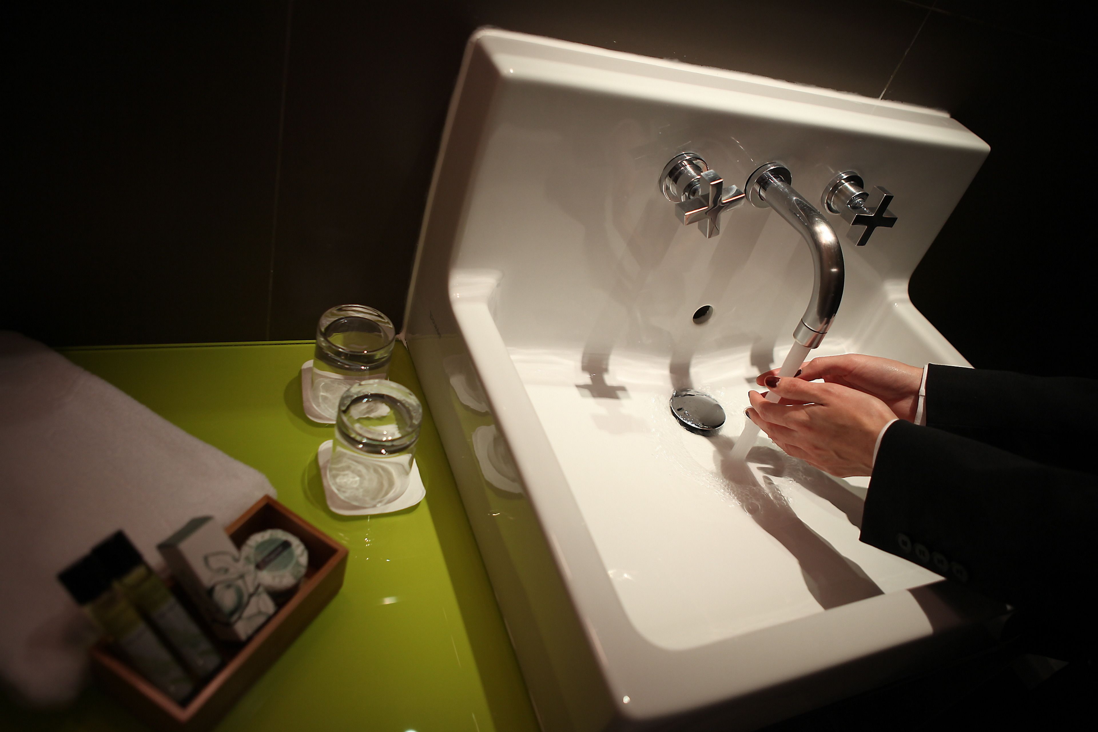A bathroom sink with a chrome faucet, a green countertop, and a box of toiletries.