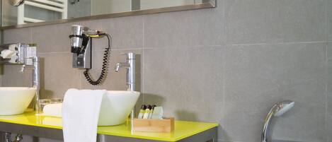A modern bathroom with a large mirror, two sinks, a bathtub, and a towel hanging on the wall.