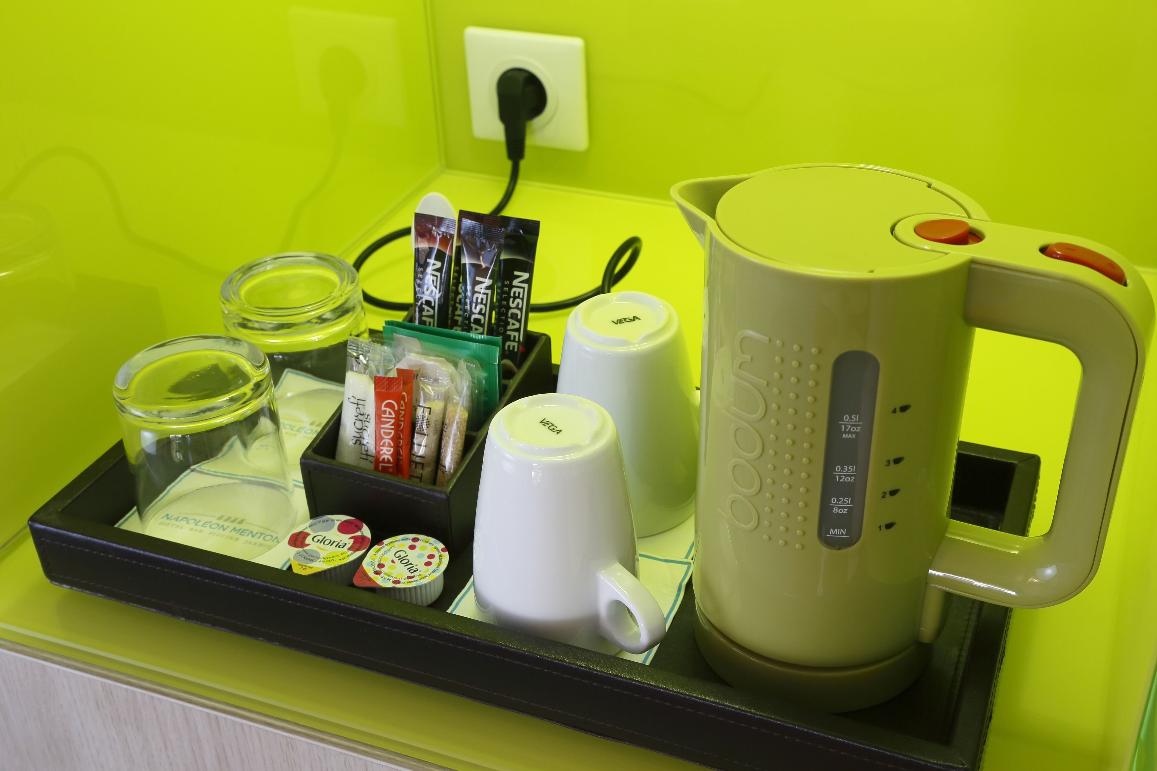 Un plateau contenant une machine à café, une tasse, un bocal en verre et quelques aliments emballés.