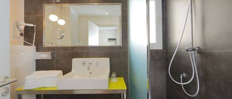 A modern bathroom with a sink, mirror, and shower.