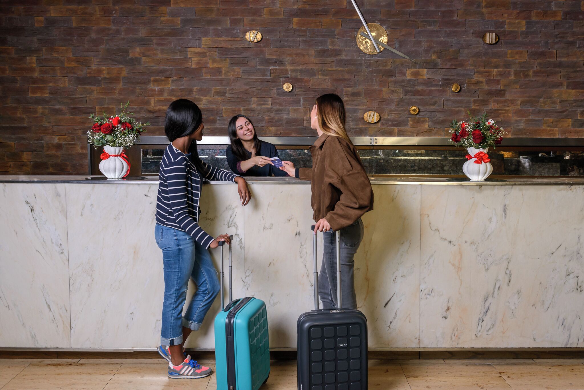A reception desk with a marble counter, a brick wall, and two flower vases.