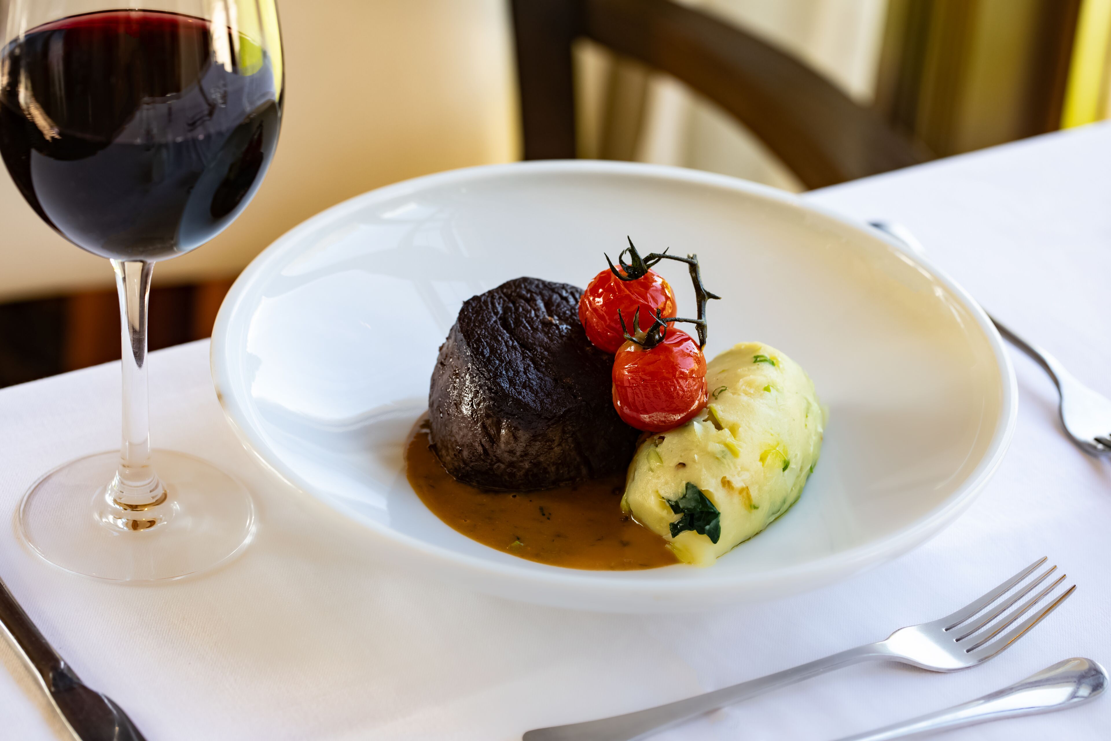 Prato de comida com um copo de vinho tinto sobre uma mesa.