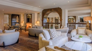 A spacious lobby with multiple seating areas, a fireplace, and a view of the kitchen area. - The Brehon Hotel & Spa (Killarney)