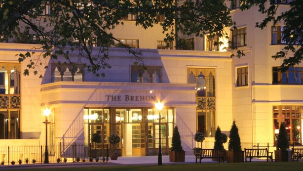 A building with a sign reading "THE BREHOUS" at the entrance, featuring a grand staircase, potted plants, and a well-lit facade. - The Brehon Hotel & Spa (Killarney)