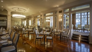 A spacious dining area with multiple tables and chairs, large windows, and a chandelier. - The Brehon Hotel & Spa (Killarney)