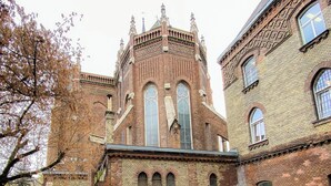 Een historisch bakstenen gebouw met boogvensters en een opvallende toren.