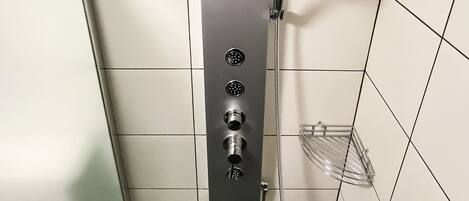 Une douche moderne dotée d’un pommeau de douche à effet pluie, d’un pommeau de douche à main et d’un flexible de douche à main.