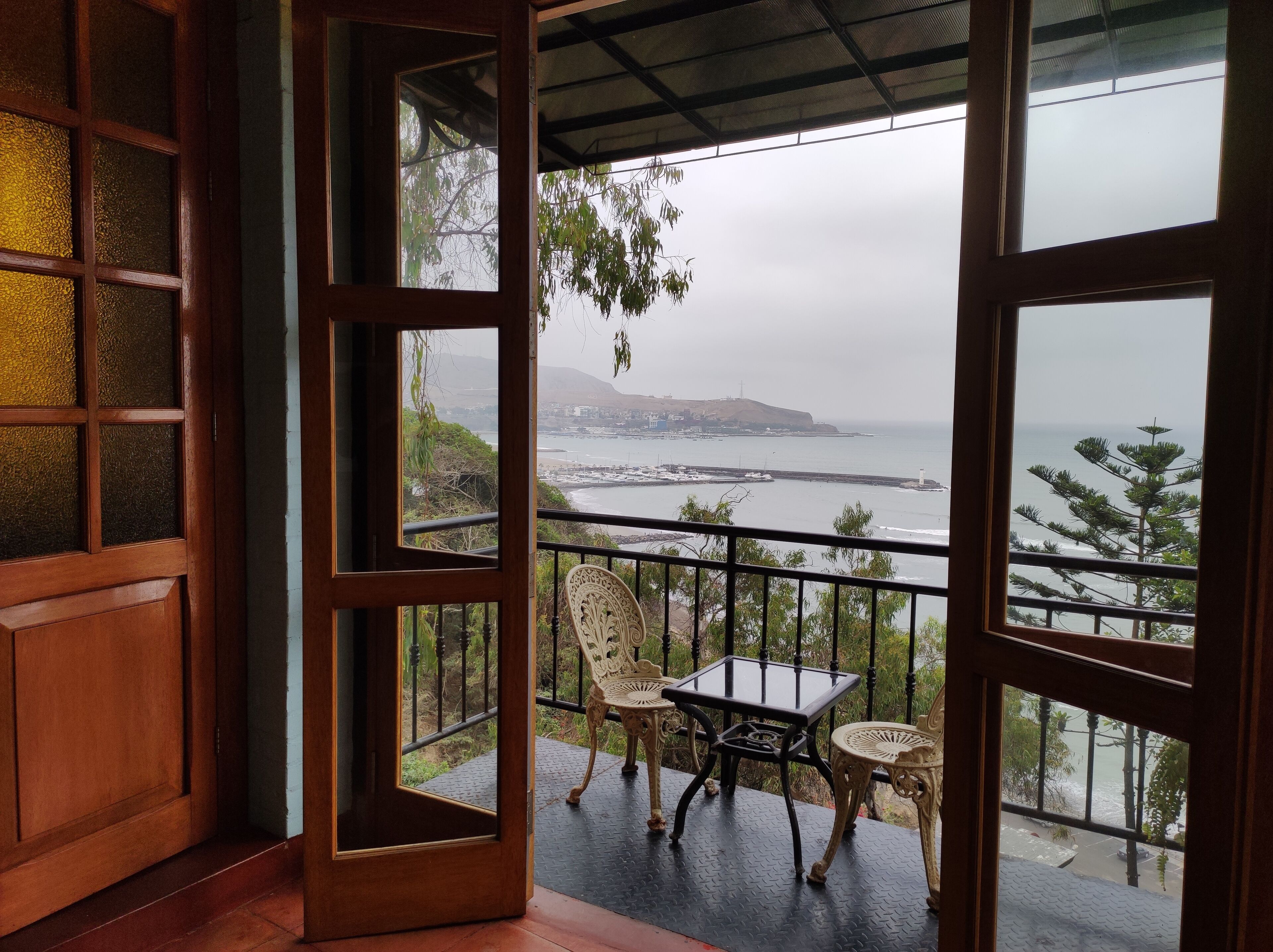 A balcony with a view of the sea, a chair, and a table.