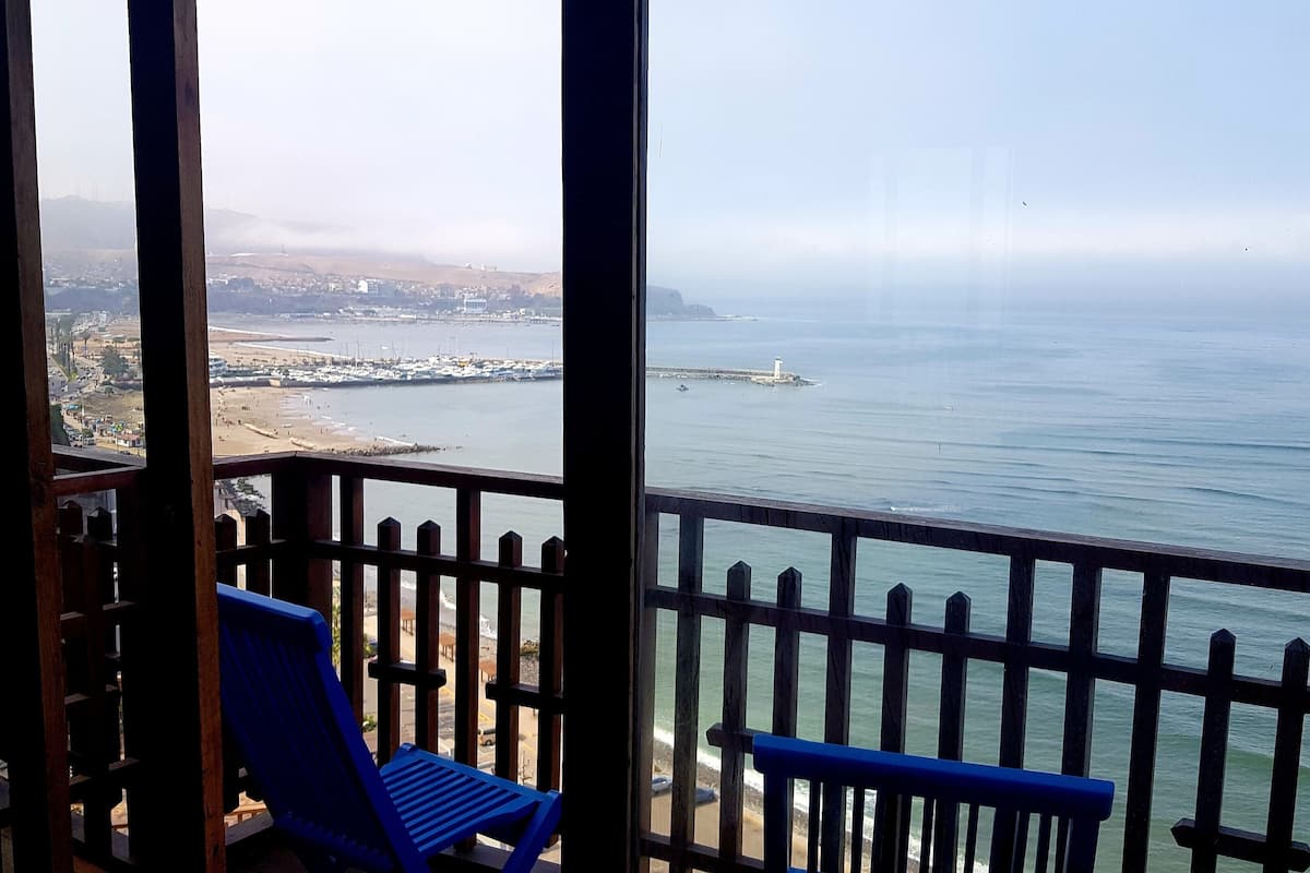 Un balcó amb vista al mar, un far i un poble llunyà.