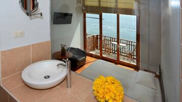 Un baño con lavamanos, espejo y un jarrón de flores amarillas.