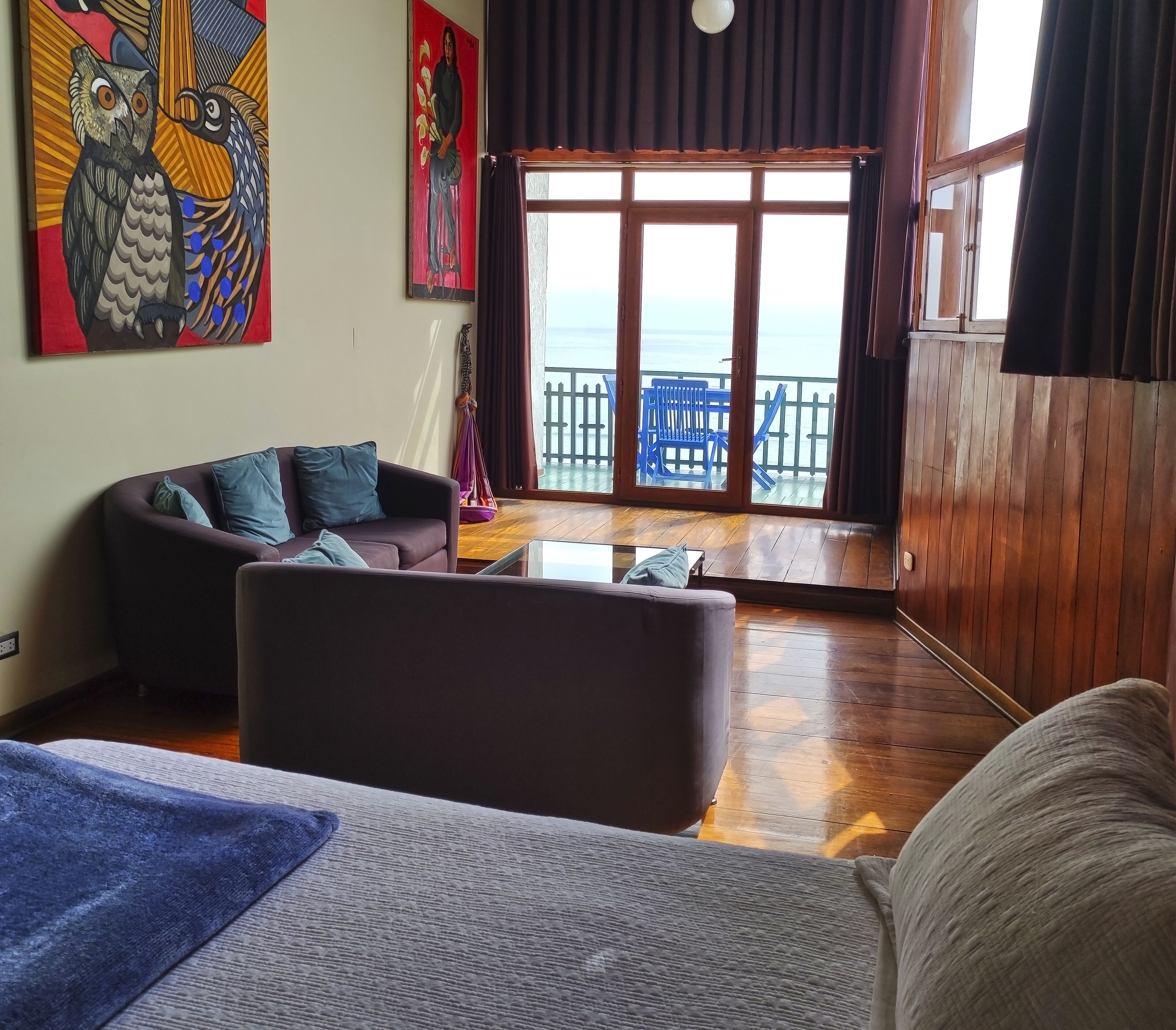 A living room with a sofa, a coffee table, and a view of the sea through large windows.