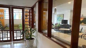 A reception area with a Christmas tree, a potted plant, and a view of a dining area with tables and chairs. - Hotel Acosta (Iquitos)