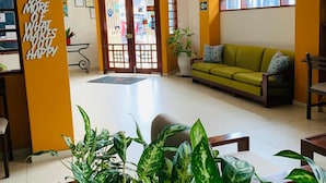 A lobby with a green sofa, a reception desk, and a wall with motivational quotes. - Hotel Acosta (Iquitos)