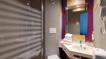 A modern bathroom with a glass shower enclosure, a sink with a mirror, and a visible toilet.