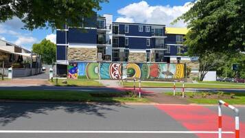 A multi-story building with a modern design, a mural on the facade, and a red bike lane.