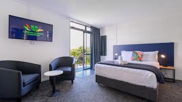 A hotel room with a bed, a TV, a chair, and a small table.
