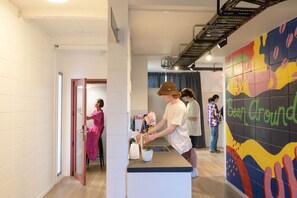 Un espace d’accueil avec un comptoir, une fresque murale colorée et un escalier en arrière-plan.