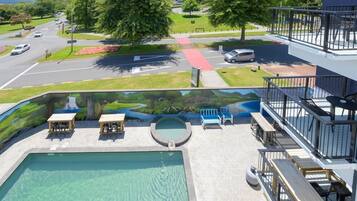 A swimming pool with lounge chairs and a view of a road and greenery.