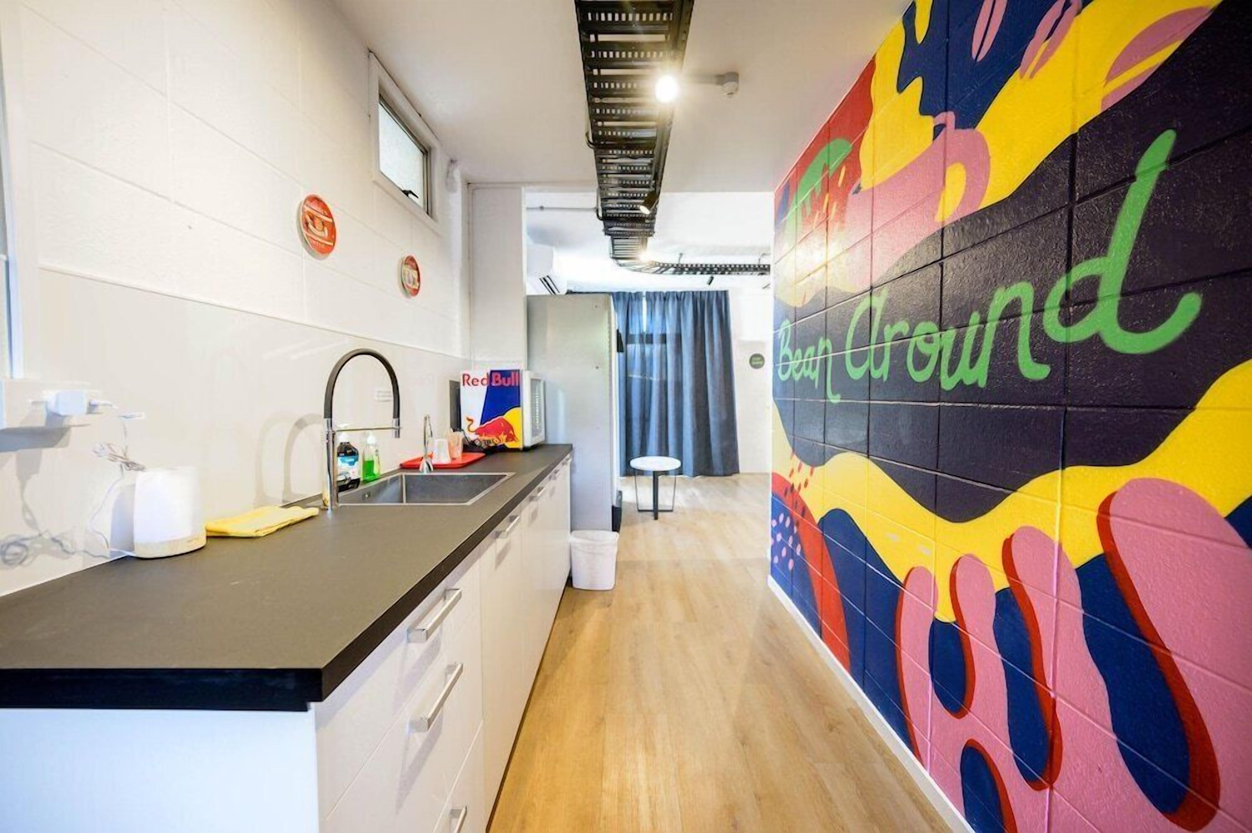 A modern kitchen with a black countertop, white cabinets, and a colorful wall mural.