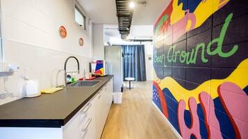 A modern kitchen with a black countertop, white cabinets, and a colorful wall mural.