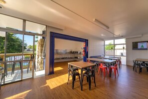 A spacious room with a large window, a kitchen area, and a dining table with chairs. - Base Rotorua - Hostel (Rotorua)