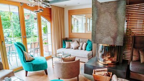 Una sala de estar moderna con un sofá, sillones, una mesa de centro de vidrio y una chimenea.