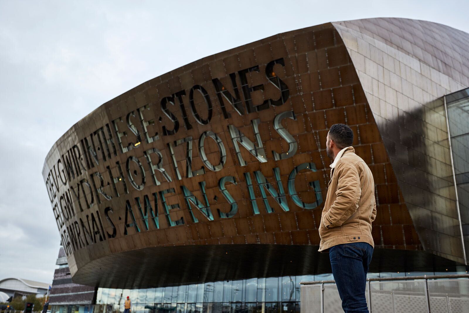 Ein modernes Gebäude mit einer geschwungenen Fassade und großen, metallischen Lettern, die "CELEGWRITHE STONES HORIZONS" ausschreiben.