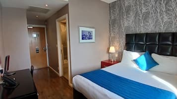 A hotel room with a bed, a desk, and a nightstand.