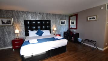 Une chambre d’hôtel avec un grand lit, deux tables de chevet avec des lampes, une commode et un miroir au mur.