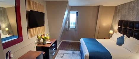 Une chambre d’hôtel avec un lit, un bureau, une chaise et un grand miroir.