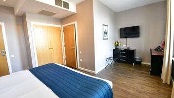 Una habitación de hotel con cama, escritorio, televisor y armario.