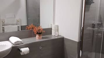 Een moderne badkamer met toilet, wastafel en douchecabine met glazen wanden.