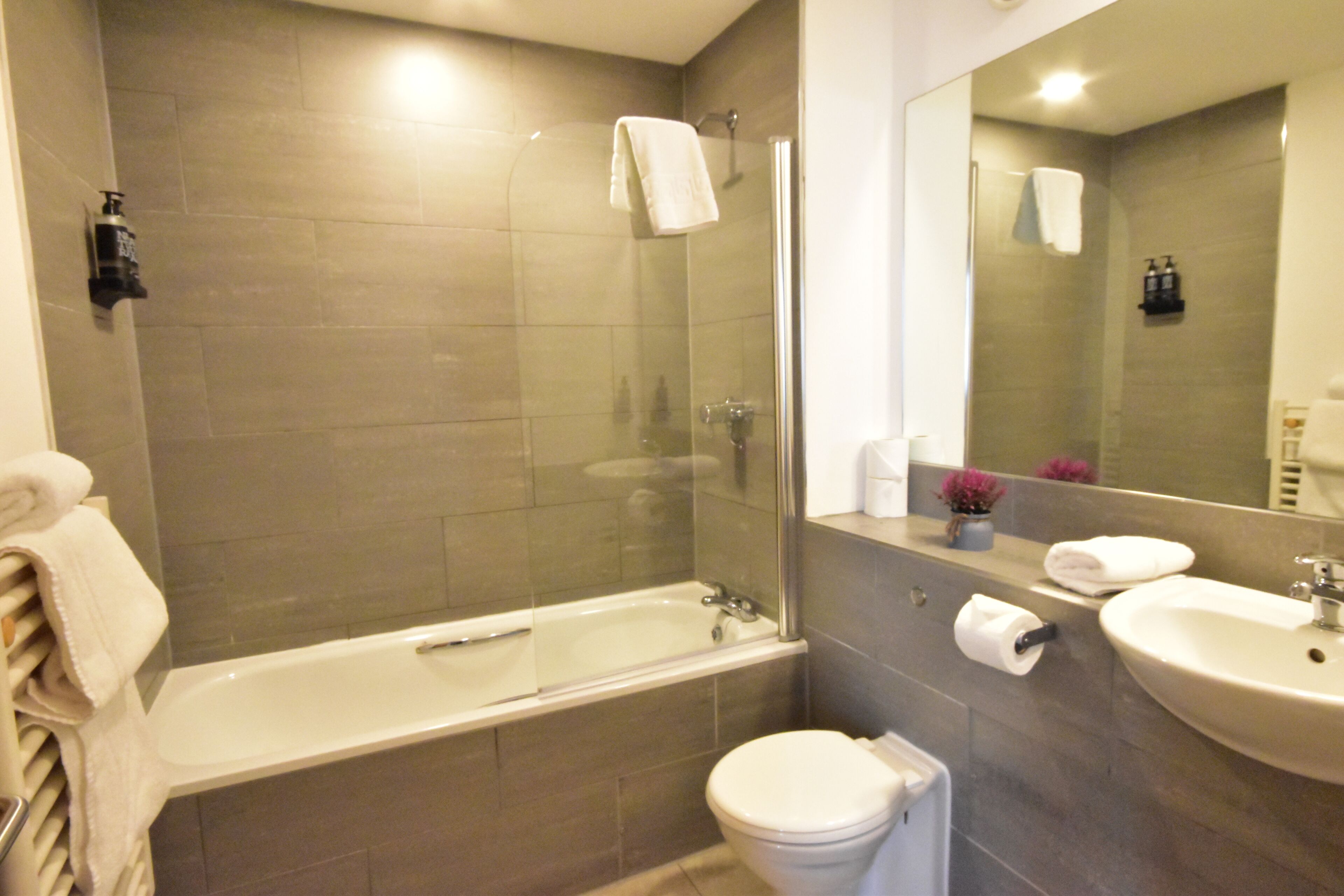 Un baño moderno con ducha envuelta en vidrio, bañera, inodoro y lavabo.