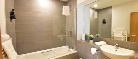 Ein modernes Badezimmer mit einer Glasdusche, einer freistehenden Badewanne, einer Toilette und einem Waschbecken.
