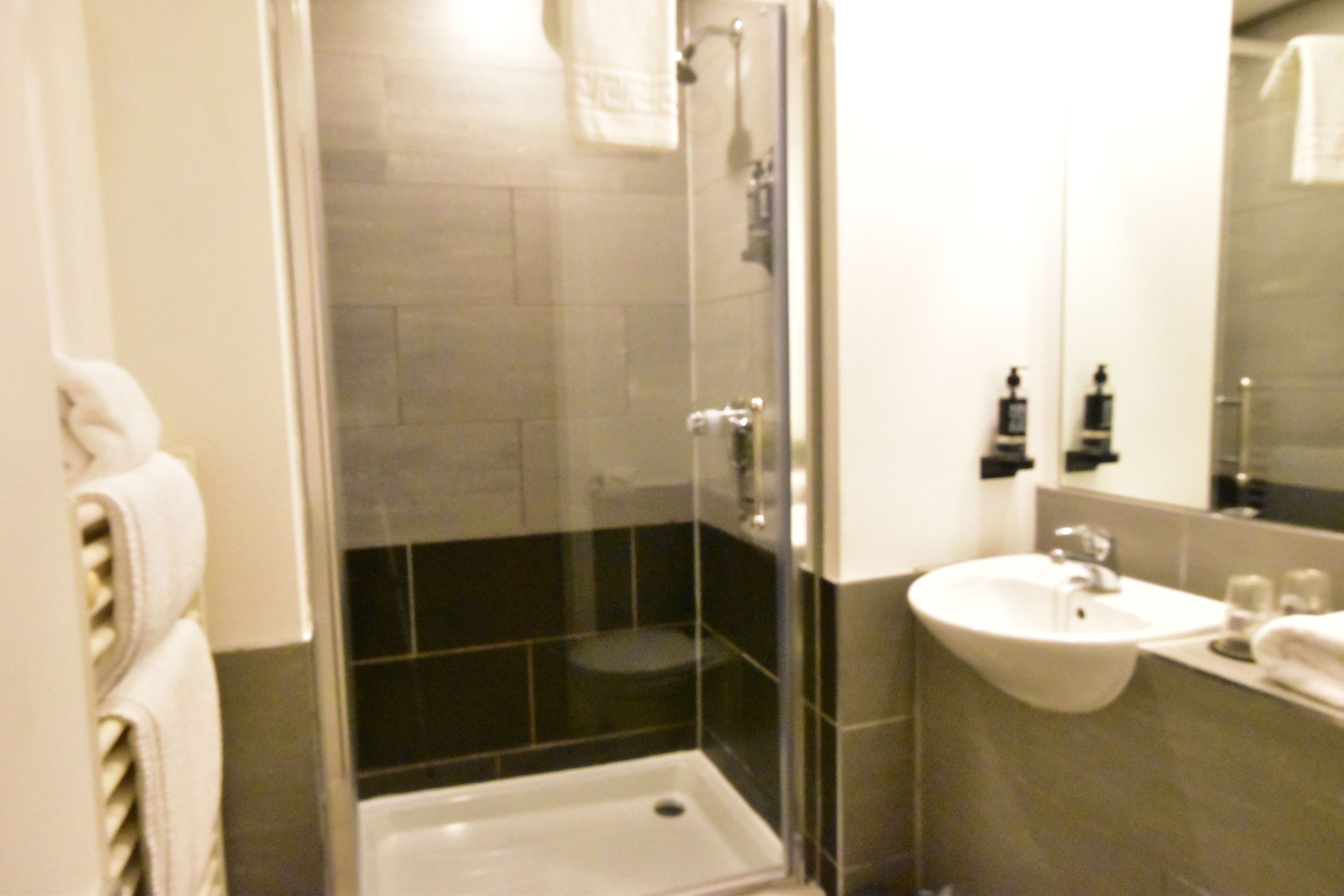 Un baño con ducha de vidrio, lavamanos y espejo.