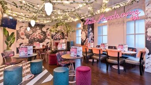 A cozy cafe with floral wallpaper, round tables, and comfortable seating. - Royal Hotel Cardiff by Belvilla (Cardiff)