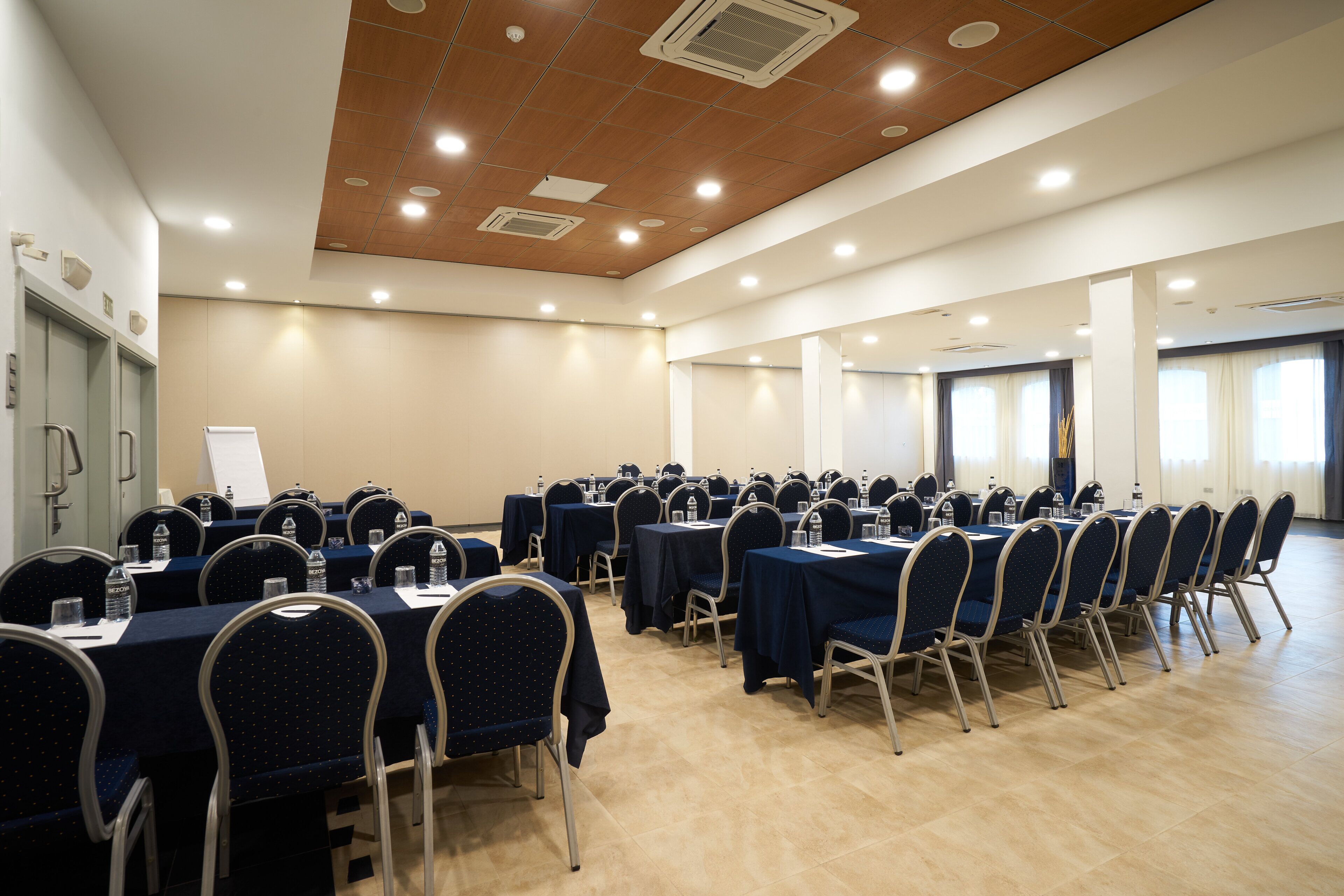 A conference room with multiple tables and chairs, equipped with water bottles and nameplates.