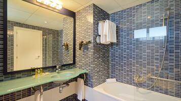 Een moderne badkamer met een glazen wastafel, een grote spiegel, een badkuip en een douche.
