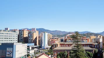A cityscape with a variety of buildings, including a prominent hotel with a red roof and a modern building with a sign for 'Mercadona'.
