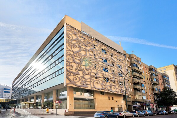 A modern building with a unique facade featuring intricate metalwork and large windows.