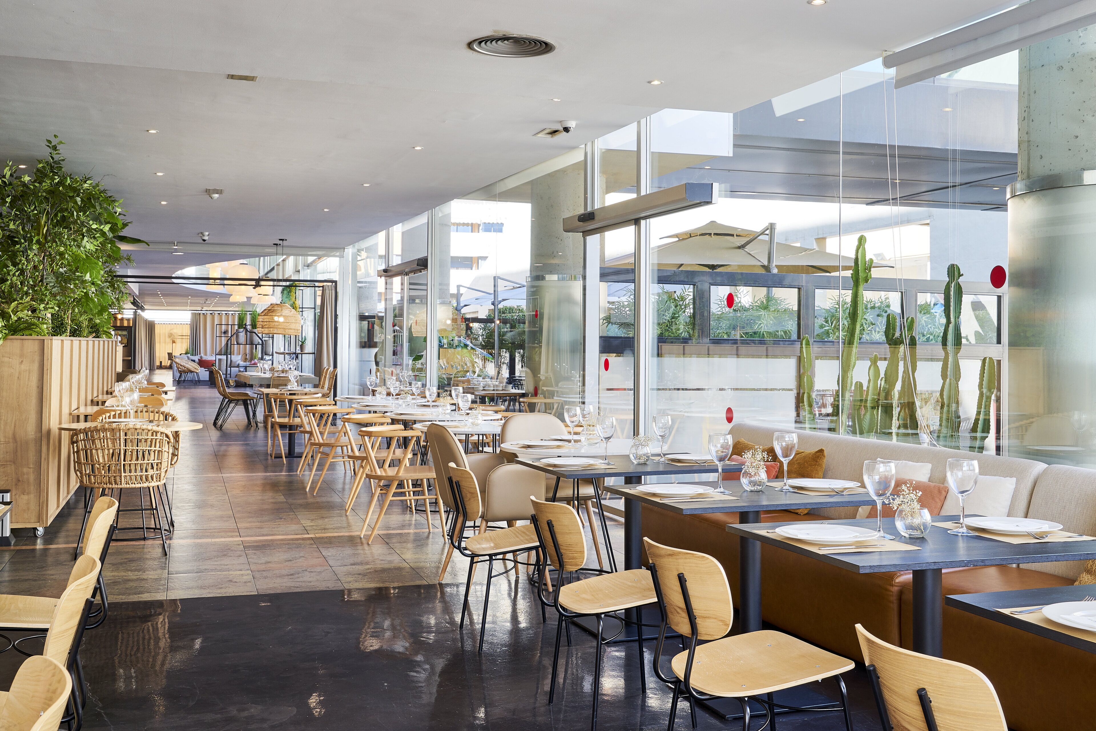 Un restaurante moderno con un amplio comedor, mesas y sillas de madera.