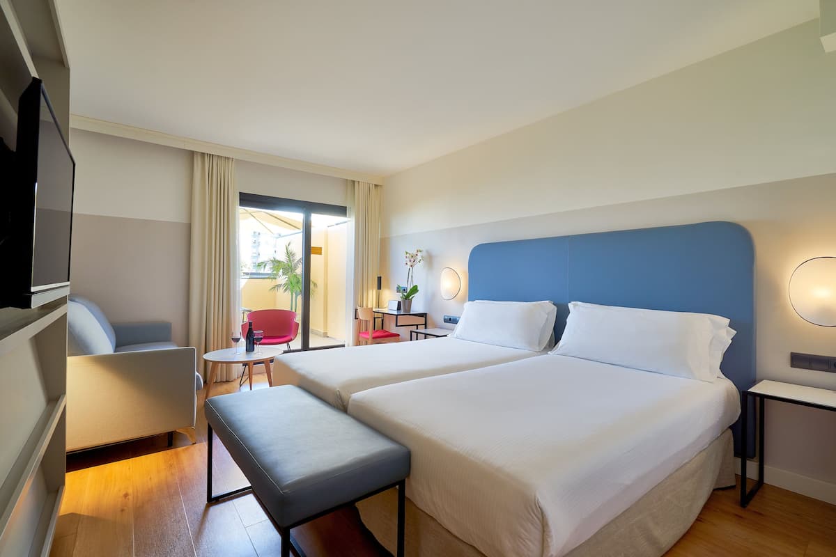 Una habitación de hotel con dos camas, un escritorio, una silla y un banco.