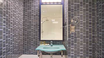 A bathroom with a large mirror, a sink, and a shower.